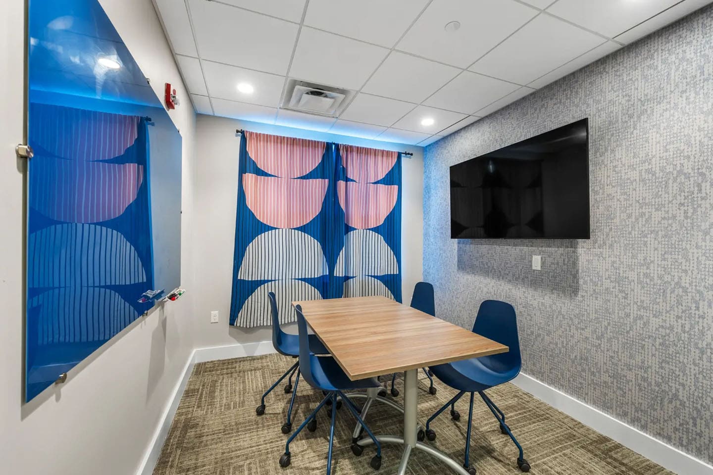 Private study area that has a dry-erase board, table and seating, as well as a TV.